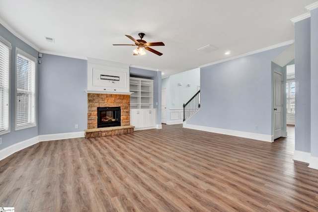 unfurnished living room with hardwood / wood-style floors, crown molding, a fireplace, and ceiling fan