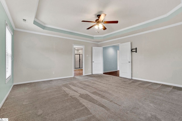 empty room with crown molding, carpet floors, a raised ceiling, and ceiling fan