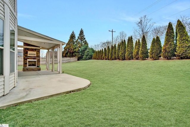 view of yard featuring an outdoor stone fireplace and a patio area