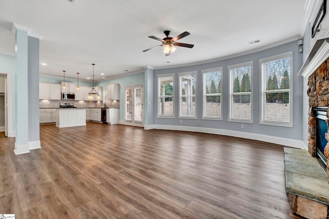 unfurnished living room featuring a stone fireplace, wood-type flooring, and ornamental molding