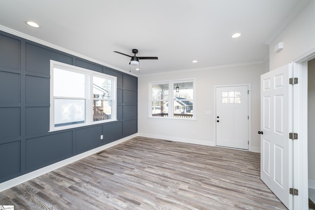 empty room with crown molding, light wood finished floors, recessed lighting, a decorative wall, and ceiling fan