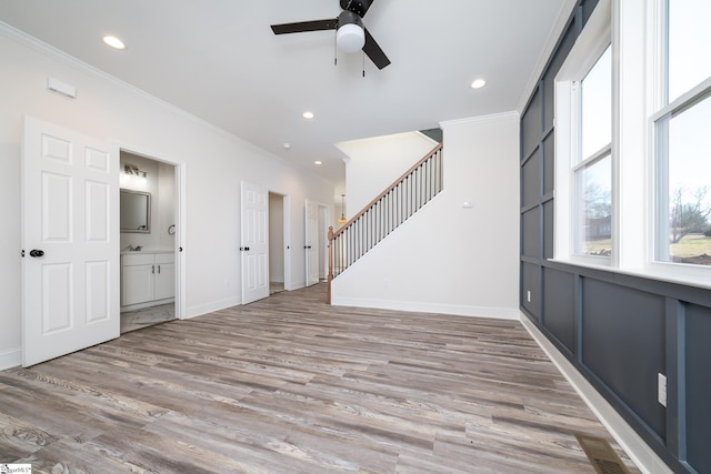 empty room with ornamental molding, light wood-type flooring, stairway, and recessed lighting