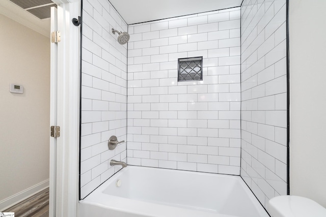 bathroom with tiled shower / bath, wood-type flooring, and toilet