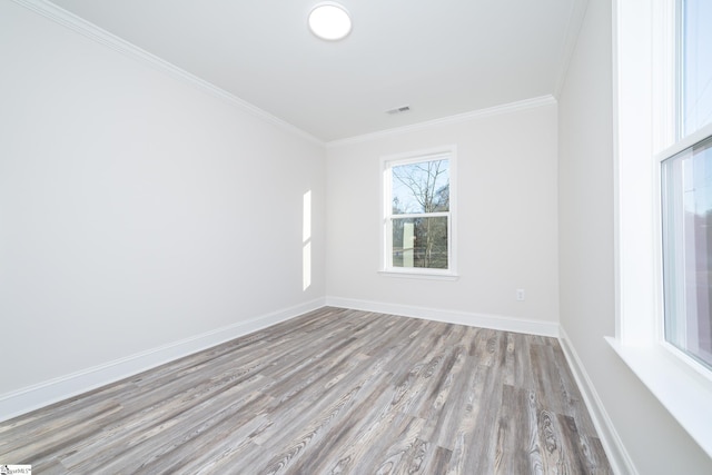 empty room with ornamental molding and light wood-type flooring