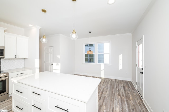 kitchen with a center island, appliances with stainless steel finishes, pendant lighting, decorative backsplash, and white cabinets