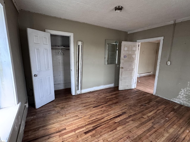 unfurnished bedroom featuring a baseboard radiator, dark hardwood / wood-style flooring, a closet, and a textured ceiling