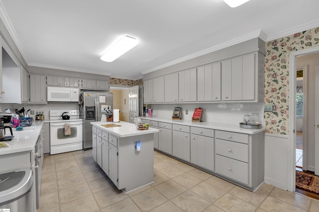 kitchen with crown molding, white appliances, gray cabinetry, and a kitchen island