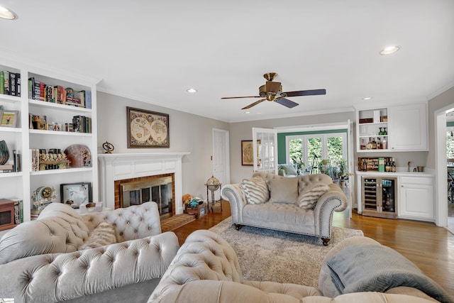 living room with bar, a fireplace, beverage cooler, and light hardwood / wood-style flooring