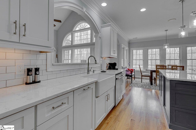 kitchen featuring pendant lighting, sink, white cabinetry, light stone countertops, and ornamental molding