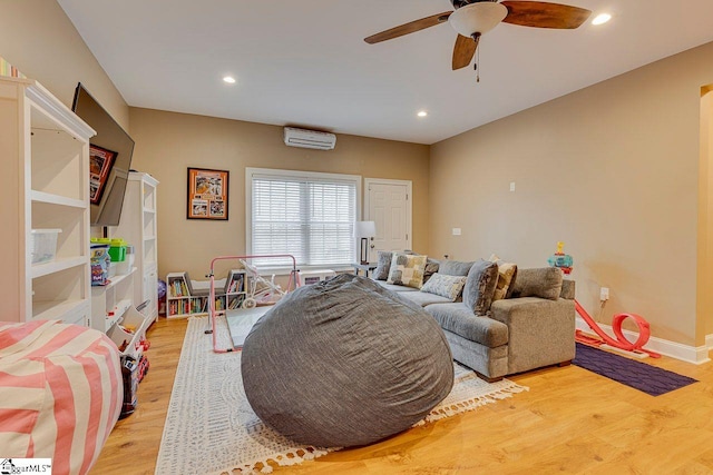 living room with ceiling fan, light hardwood / wood-style flooring, and an AC wall unit