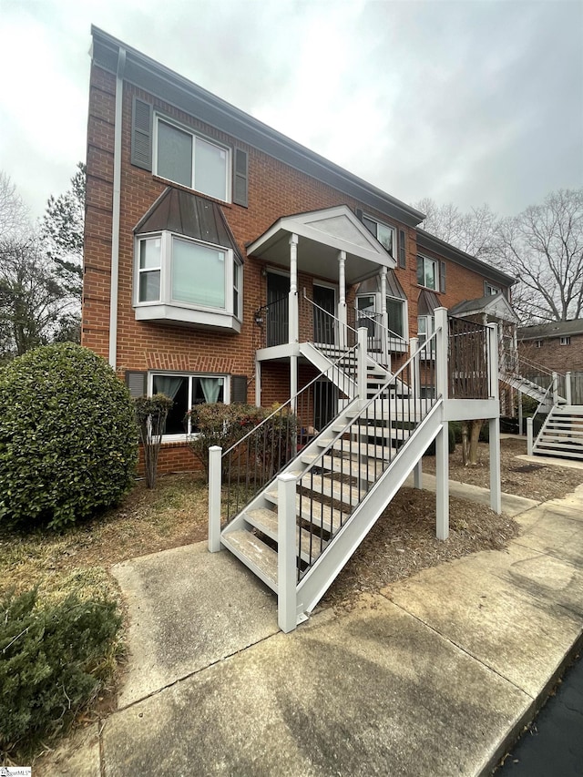 view of front of property featuring stairs and brick siding