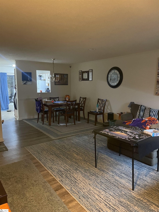 dining space with baseboards, wood finished floors, and a notable chandelier