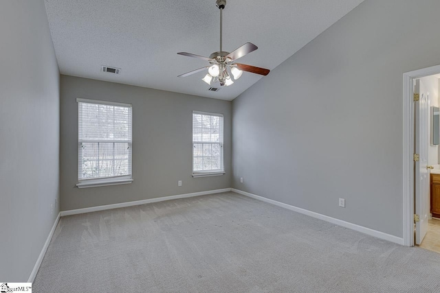 carpeted empty room with vaulted ceiling, ceiling fan, and a textured ceiling