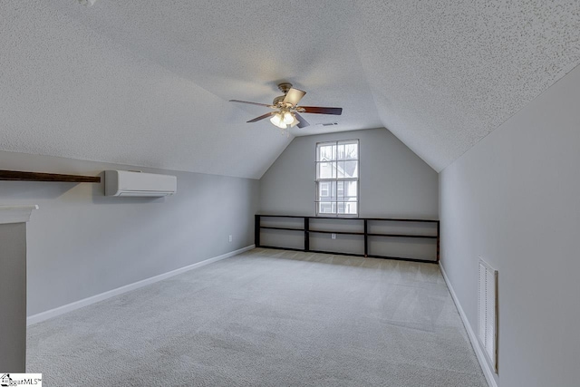 additional living space with lofted ceiling, a textured ceiling, light carpet, an AC wall unit, and ceiling fan