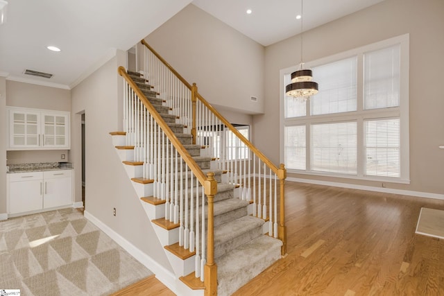 stairway featuring hardwood / wood-style floors, a towering ceiling, a wealth of natural light, and a chandelier