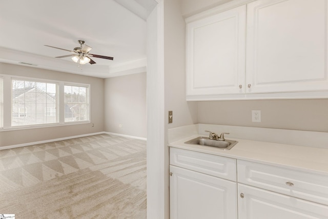 kitchen featuring ceiling fan, sink, light carpet, and white cabinets