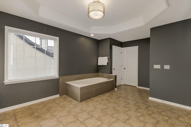 bathroom with a raised ceiling, crown molding, and tiled tub