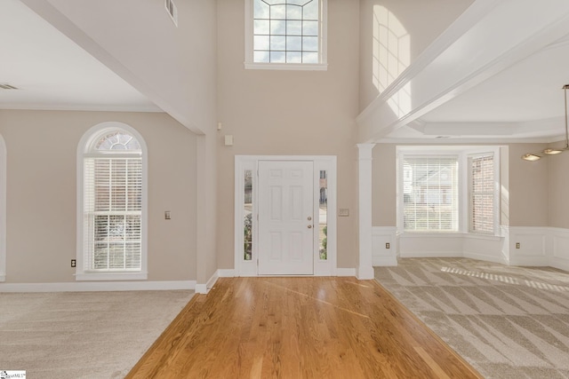 entryway featuring a high ceiling, ornamental molding, and carpet