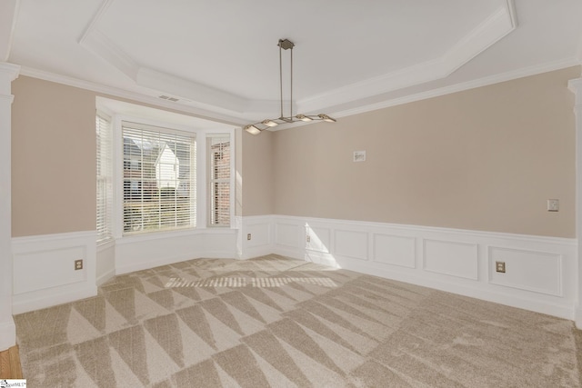 empty room featuring crown molding, a tray ceiling, and light colored carpet