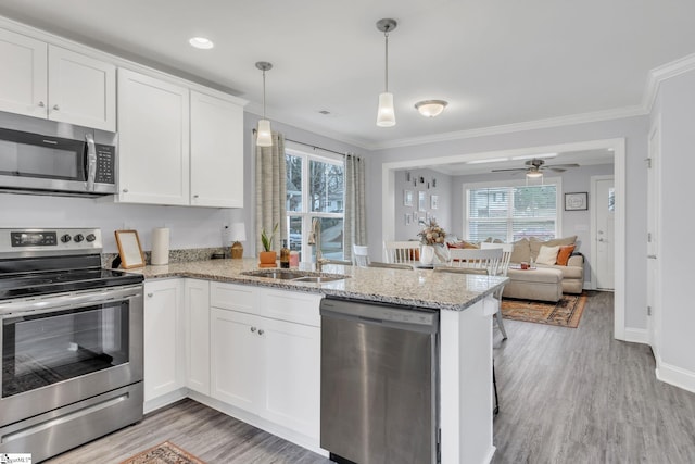 kitchen featuring white cabinetry, hanging light fixtures, stainless steel appliances, and kitchen peninsula