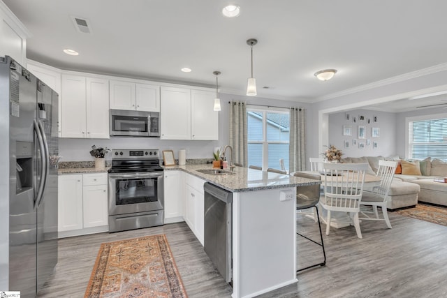 kitchen with pendant lighting, sink, stainless steel appliances, white cabinets, and kitchen peninsula