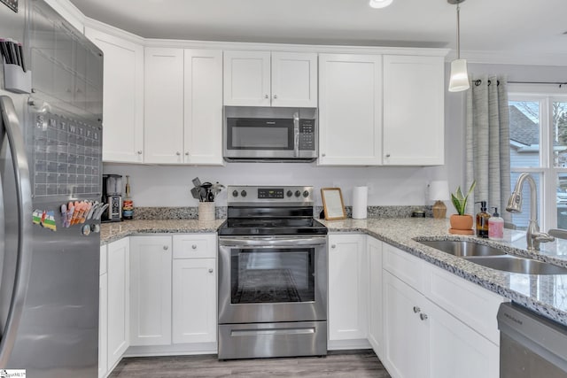 kitchen featuring sink, pendant lighting, stainless steel appliances, light stone countertops, and white cabinets