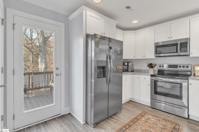 kitchen with stainless steel appliances, white cabinetry, and light stone counters