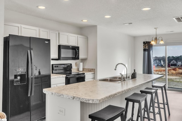 kitchen with white cabinets, a kitchen island with sink, sink, and black appliances