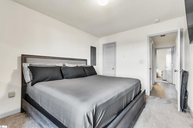 bedroom featuring light colored carpet, electric panel, and a textured ceiling