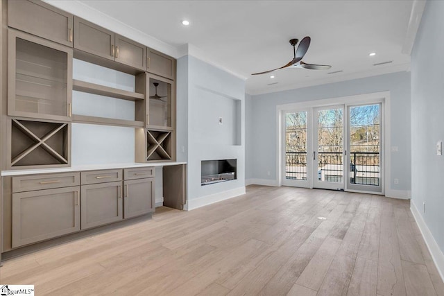 unfurnished living room featuring crown molding, ceiling fan, and light wood-type flooring