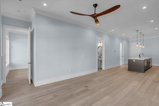 unfurnished living room featuring ceiling fan, ornamental molding, sink, and light hardwood / wood-style flooring