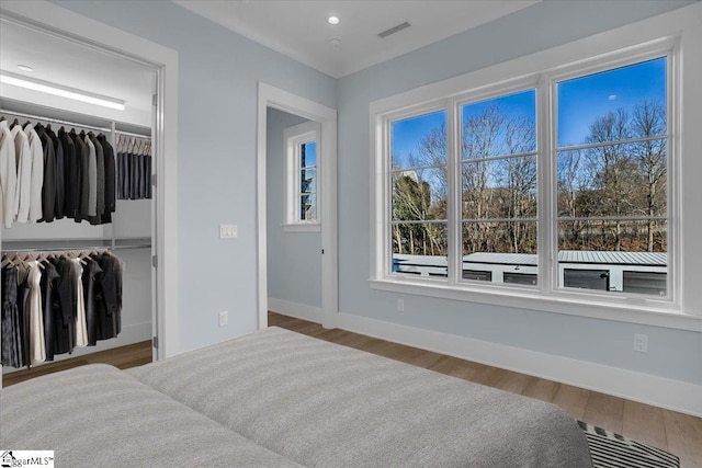 bedroom with a spacious closet, hardwood / wood-style floors, and a closet