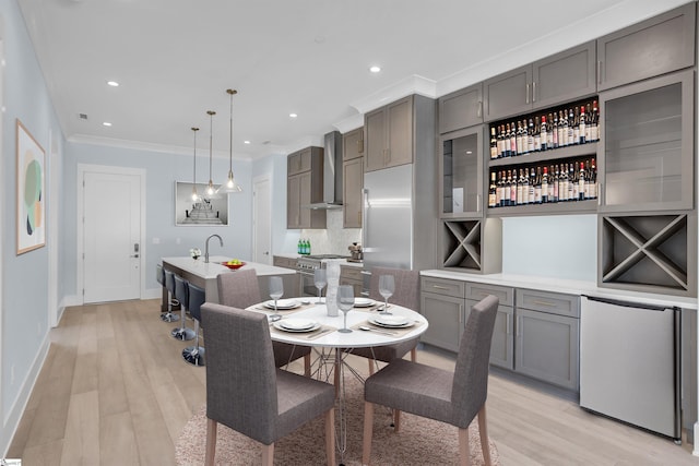 dining area with crown molding, sink, and light hardwood / wood-style flooring