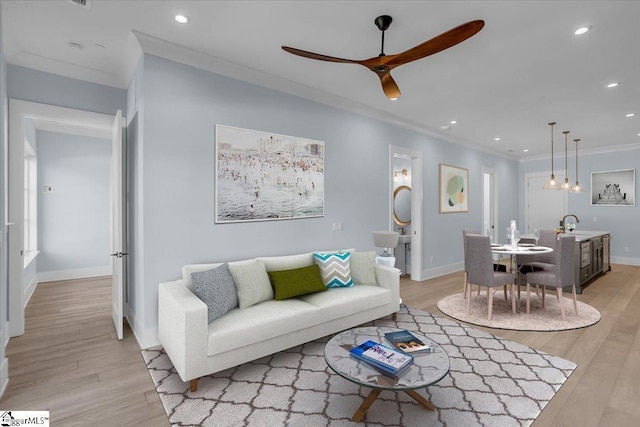 living room featuring crown molding, ceiling fan, and light hardwood / wood-style floors