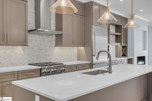 kitchen with sink, light stone counters, range, decorative light fixtures, and wall chimney range hood