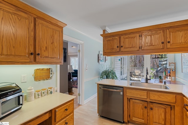 kitchen with ornamental molding, appliances with stainless steel finishes, sink, and light hardwood / wood-style flooring