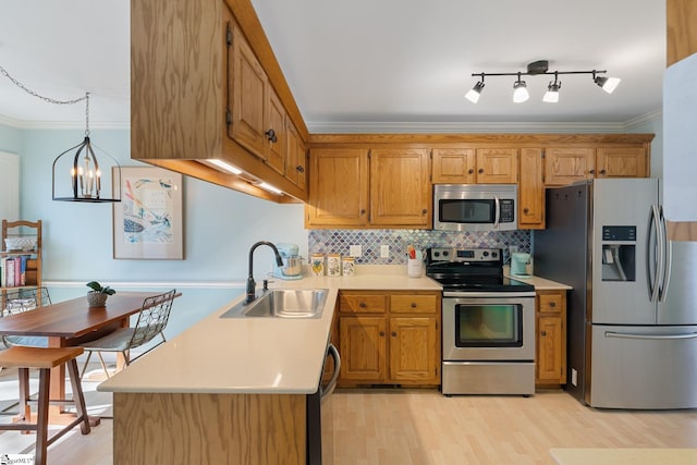 kitchen with sink, backsplash, hanging light fixtures, stainless steel appliances, and ornamental molding