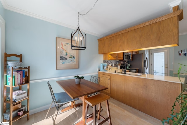 kitchen featuring sink, crown molding, hanging light fixtures, kitchen peninsula, and stainless steel appliances