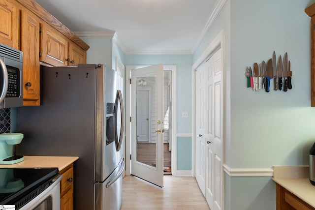 kitchen featuring crown molding, appliances with stainless steel finishes, and light hardwood / wood-style floors