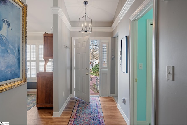 foyer featuring an inviting chandelier, crown molding, and light hardwood / wood-style floors