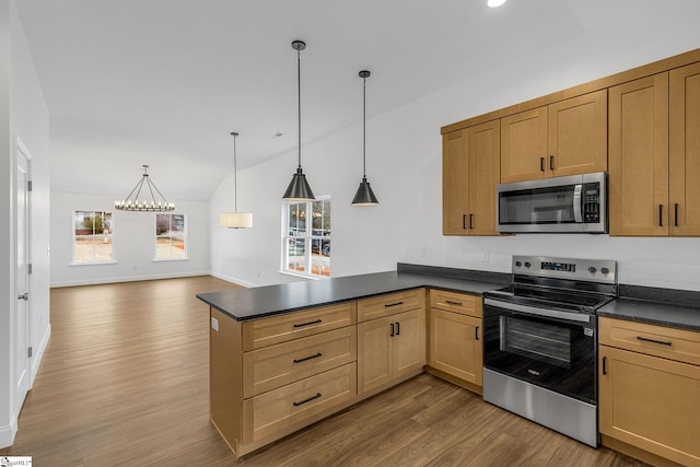 kitchen featuring vaulted ceiling, appliances with stainless steel finishes, hanging light fixtures, hardwood / wood-style flooring, and kitchen peninsula