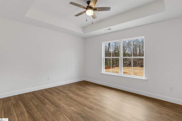 spare room featuring ceiling fan, a tray ceiling, and hardwood / wood-style floors