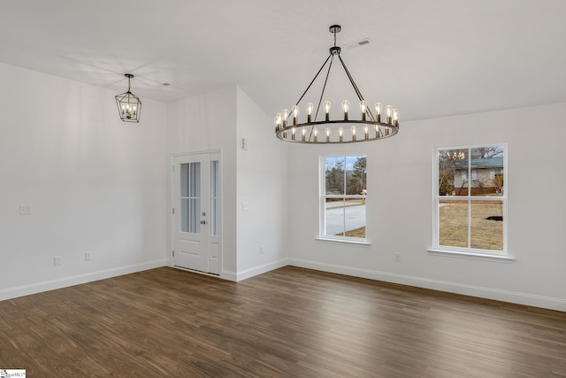 spare room with dark wood-type flooring and a chandelier