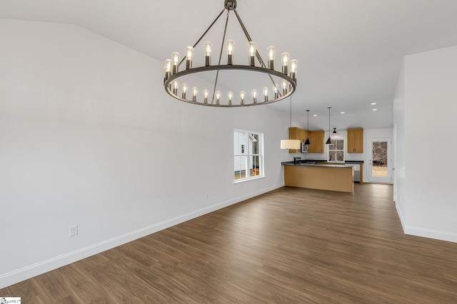 unfurnished living room with vaulted ceiling, dark hardwood / wood-style floors, and a notable chandelier