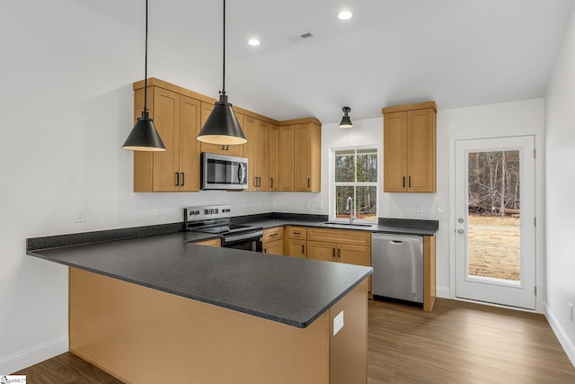 kitchen featuring hanging light fixtures, appliances with stainless steel finishes, sink, and kitchen peninsula