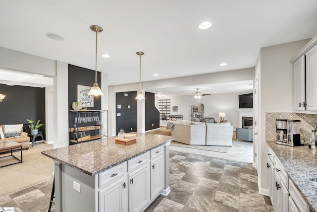 kitchen featuring a kitchen bar, white cabinetry, tasteful backsplash, decorative light fixtures, and a kitchen island