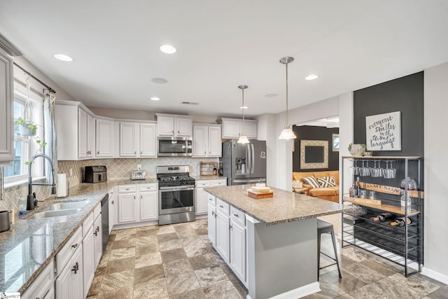 kitchen featuring sink, a center island, hanging light fixtures, appliances with stainless steel finishes, and white cabinets