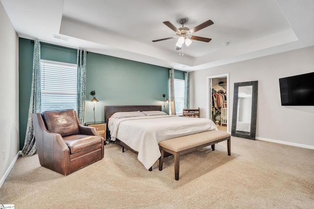 bedroom with a closet, a walk in closet, and a tray ceiling