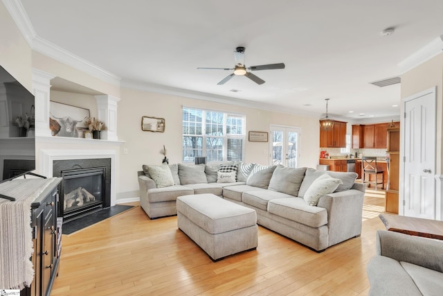 living room with crown molding, ceiling fan, and light hardwood / wood-style flooring