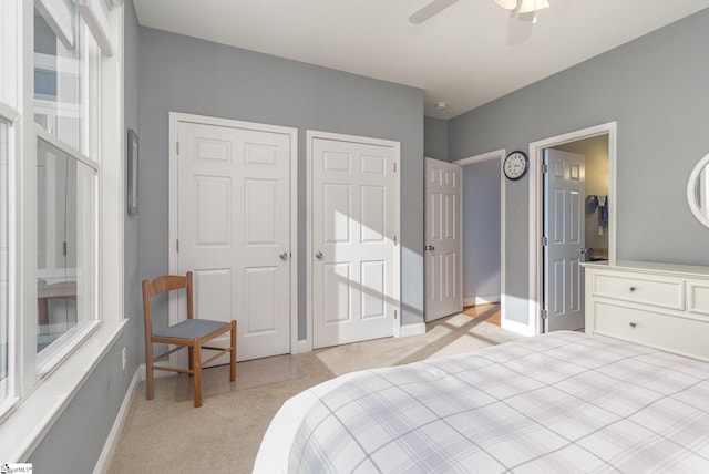 bedroom featuring light carpet, ensuite bath, and ceiling fan